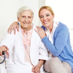elder woman and caregiver smiling in front of the camera