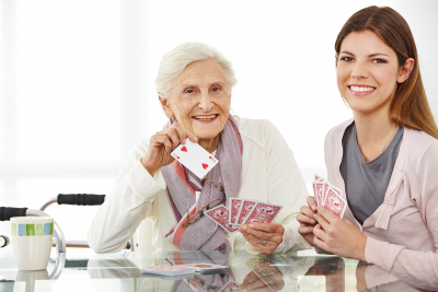 caregiver playing cards with happy elder woman
