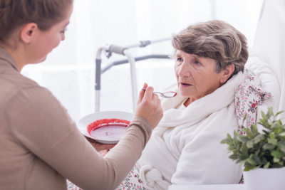 caregiver feeding an elder woman